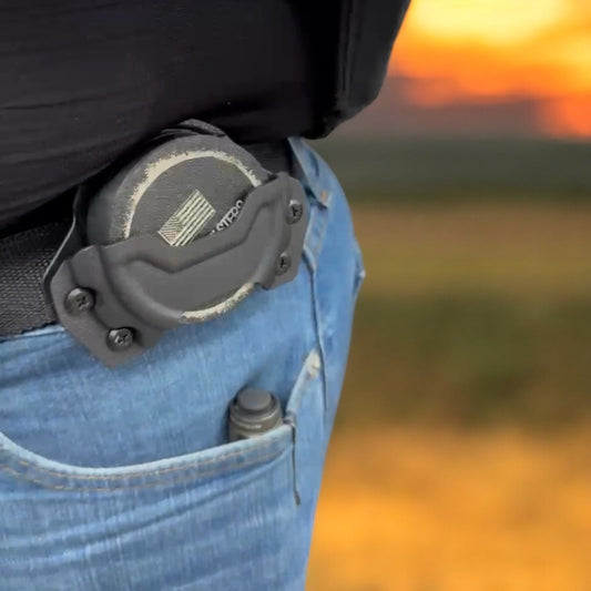 Person wearing a tactical belt with a clip against a sunset background