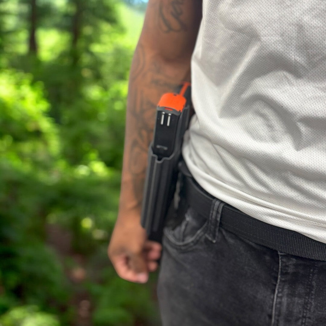 Person wearing a tool belt with a tool in a forest setting