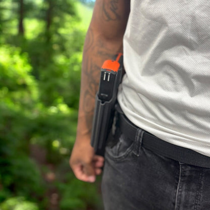 Person wearing a tool belt with a tool in a forest setting