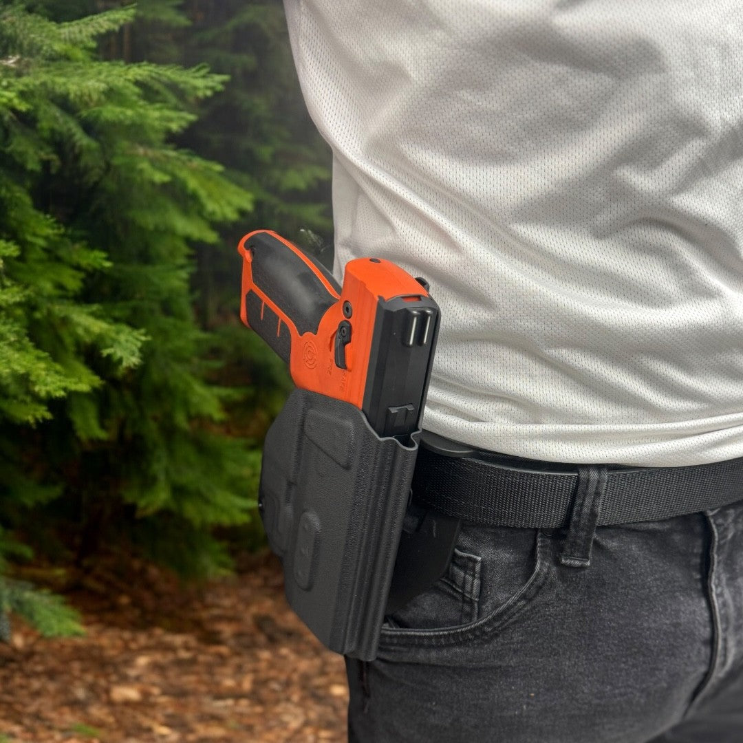 Person wearing a black and orange tool belt with a tree in the background