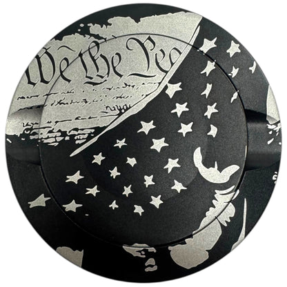Circular object with 'We the People' engraving and star patterns on a black background